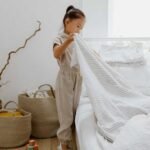 child making bed in home bedroom