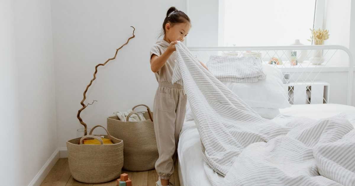 child making bed in home bedroom