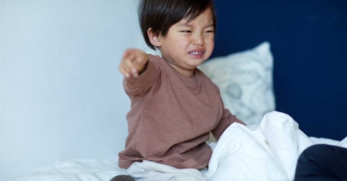 child is going to fold clothes on bed but crying