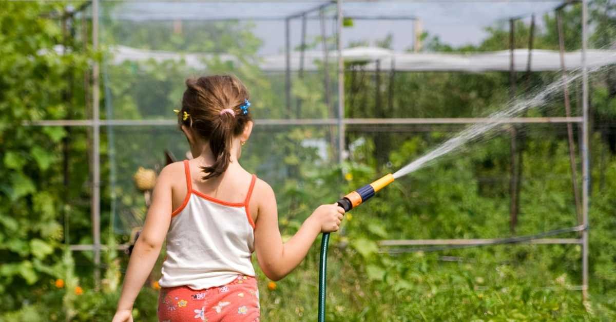 child watering plants garden